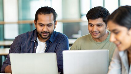 Indian startup team analyzing business reports and graphs on laptops in a co-working environment
