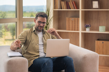 Young home-based online therapist in virtual counseling session, focused mental health professional listening to client on video call taking notes offering support and empathy in calm domestic setting