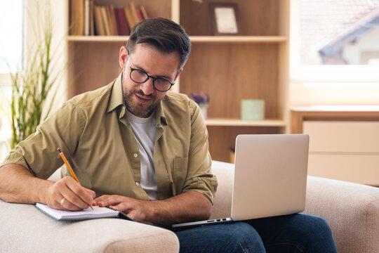 Young home-based online therapist in virtual counseling session, focused mental health professional listening to client on video call taking notes offering support and empathy in calm domestic setting