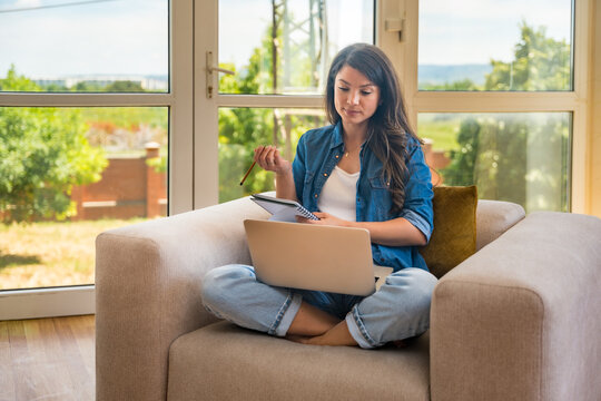 Young home-based online therapist in virtual counseling session, focused mental health professional listening to client on video call taking notes offering support and empathy in calm domestic setting