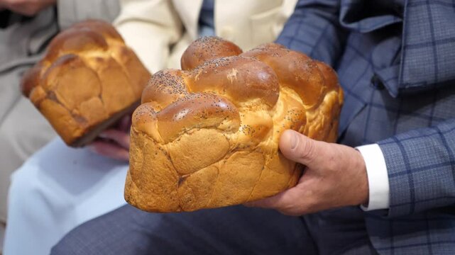 People hold traditional bread in their hands to bless the bride and groom.