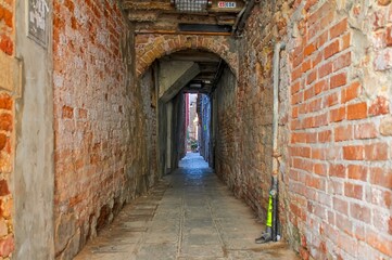 Venice, Italy - Narrow passage with brick walls leading to an arch in Venice