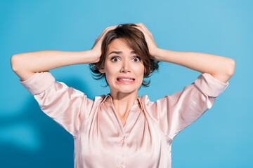 Young woman in satin blouse expressing surprise against a blue background