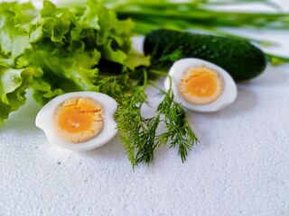 'sliced ​​eggs and dill, on a blurred background cucumber, lettuce and onion in the upper part...