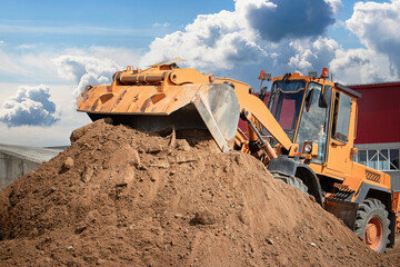 Heavy machinery operates on construction site moving dirt during a bright day with scattered clouds