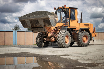 Fototapeta premium Heavy machinery operates at a construction site under a cloudy sky in early afternoon