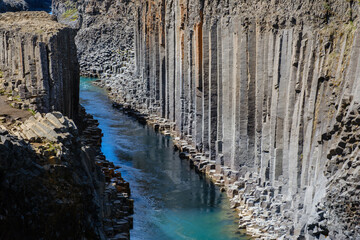 Majestic basalt columns rise from the clear waters of Studlagil Canyon, inviting adventure seekers...