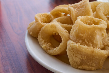Traditional Spanish tapa featuring “calamares a la romana”, squid rings battered and fried to a crisp golden texture, served hot in a restaurant. Classic dish in Spanish coastal cuisine.