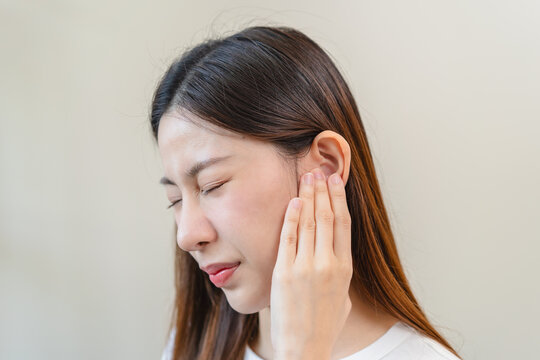 ear problem concept, Young woman touching her ear feel pain from inflammation.