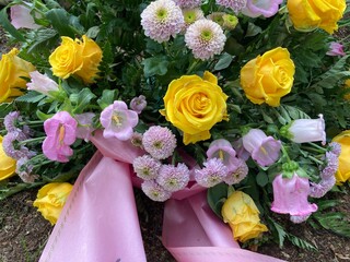 Gesteck mit frischen Blumen zur Beerdigung in gelb und rosa auf dem Friedhof