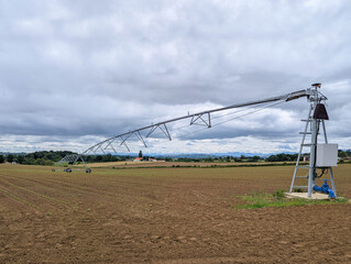 Sistema moderno de rega agrícola com irrigação por pivô central que cobre uma grande área em meio à fazenda rural