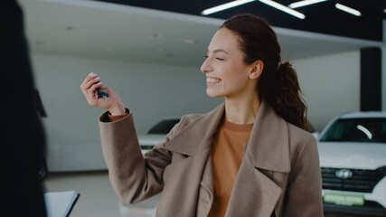 Smiling woman receives car keys from manager in dealership - Powered by Adobe