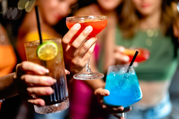 Group of friends toasting with colorful cocktails during a lively night out, showcasing vibrant drinks and festive vibes