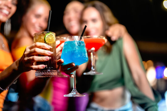 Group of friends toasting with colorful cocktails during a lively night out, showcasing vibrant drinks and festive vibes - Powered by Adobe