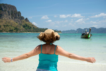 Rear view of young woman running and opening her arms observing wonderful beach