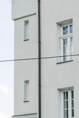 Windows with muntins reflecting blue sky on bright building facade, architectural detail showing symmetry, light, and classic window design elements