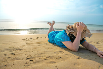 Rear View of young model lying with hat on beach at Patong beach