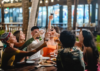 Group of diverse friends raising glasses in a joyful toast at a tropical outdoor party, celebrating together under palm trees and string lights