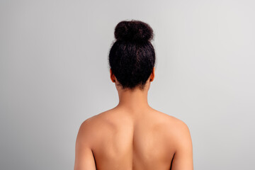 Rear view of a young woman with natural hairstyle and flawless skin against a white background