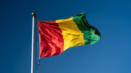 The vibrant flag of Guinea, featuring stripes of red, yellow, and green, waves proudly against a serene blue backdrop.