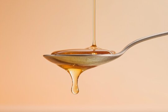 Honey flowing from spoon on gradient color background