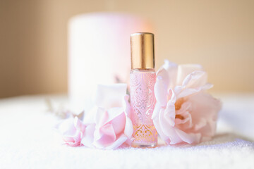 Decorated pink essential oil roller bottle with fresh roses and diffuser