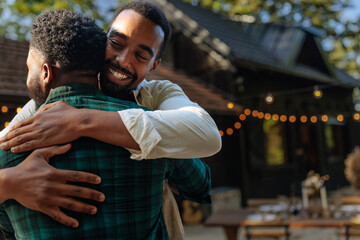 Fototapeta premium Friends hugging outdoors with a house and string lights in background