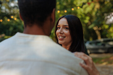Woman smiling while dancing with a man outdoors with string lights