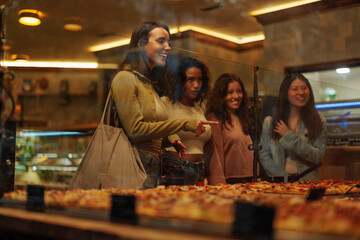 Young girl pointing at the pizza inside of a pizzeria