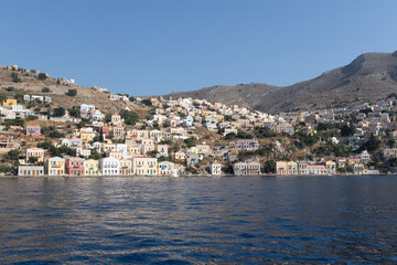 Obraz premium Case colorate sulla costa dell’isola con mare calmo e cielo azzurro..