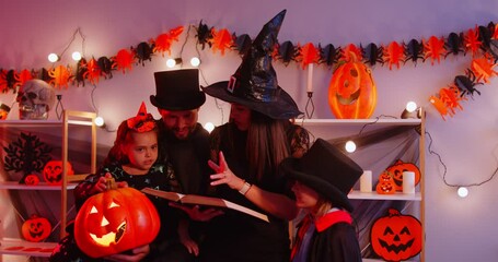 Happy Halloween celebration. Mother and father telling mystery story to their children while celebrating autumn holiday, reading book together, posing in decorated room, wearing spooky costumes - Powered by Adobe