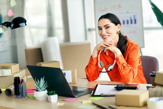 Professional entrepreneur woman working at her office desk managing ecommerce orders and deliveries with a laptop