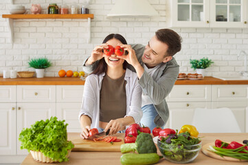 Happy funny young family couple, woman, man healthy vegans at home kitchen, vegetarian diet,...