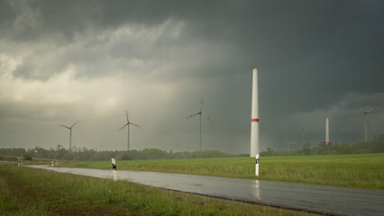 A wind turbine being built in the countryside during a downpour 