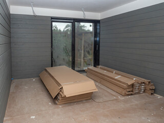 Unfinished room with wooden wall panels and packed flooring materials, prepared for interior...