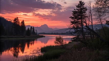 Obraz premium Sunset Serenity: A tranquil lakeside scene captures the ethereal beauty of a vibrant sunset over a serene lake. The water mirrors the colorful sky.