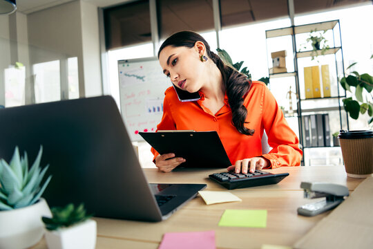 Focused businesswoman multitasking in modern office, analyzing data and managing work responsibilities effectively