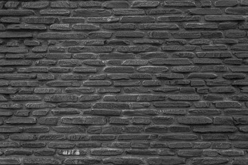 Obraz premium The black wall is made of uneven black gloomy stones. Abstract dramatic background.