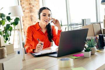 Young female entrepreneur working remotely on a laptop discussing business opportunities, wearing a...