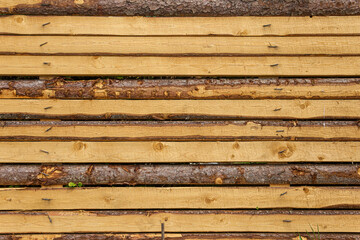 Rough-cut wooden boards. Barrier fence made of unplaned boards.