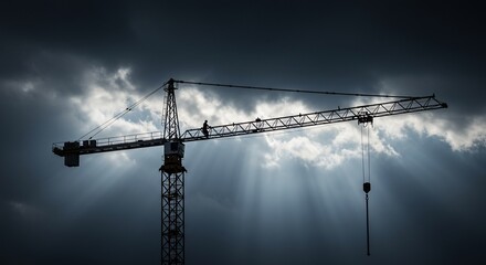 Silhouette of a construction crane against a dramatic sky with sun rays