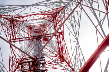 Low-angle view of a red and white telecommunications tower structure against a bright sky, highlighting modern engineering, symmetry, and industrial design.