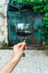 Red Wine Glass in Hand with Stone Cellar Background in France or Italy