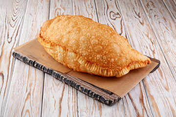Crispy deep fried cheburek on wooden board surface