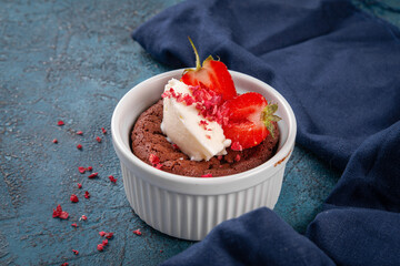 Warm chocolate fondant served in a ramekin with a scoop of vanilla ice cream and fresh strawberries. Perfect dessert for cafe menus and sweet lovers