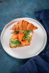 Crispy buttery croissant filled with silky smoked salmon, cucumber ribbons, fresh dill and soft cream cheese. Elegant light snack served on a white plate