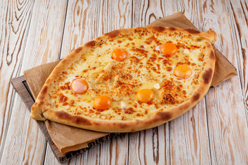 Traditional Georgian khachapuri with melted cheese and raw egg yolks on top. Baked boat-shaped...