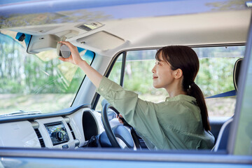 車のバックミラーを調整する日本人の女性ドライバー