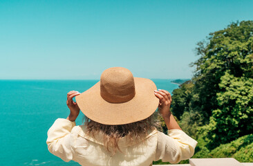 Woman in Summer Hat Looking at Sea Horizon from Cliff