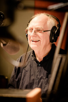 An elderly caucasian man DJs and presents his music show on live radio in Castlemaine, Australia
